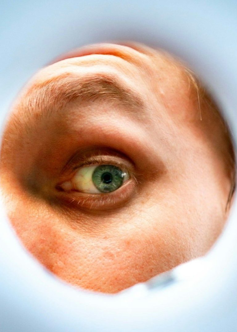 Close-up of a green eye viewed through a circular opening.