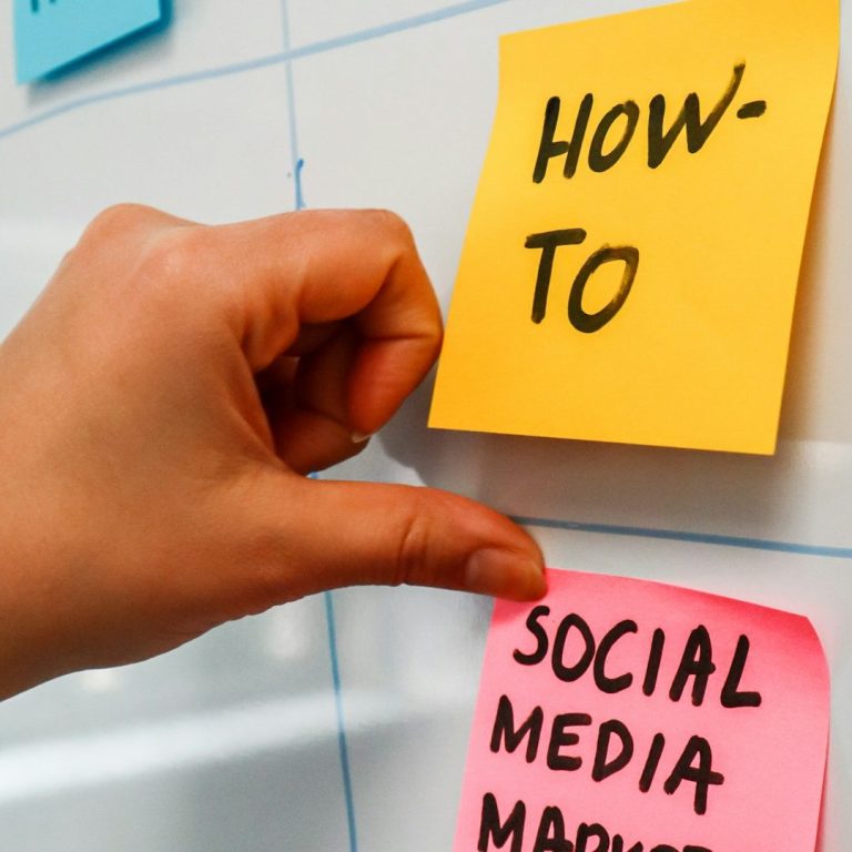 Hand placing a pink sticky note labeled "Social Media Marketing" on a board.